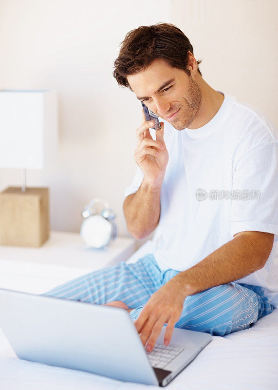 一个一边用笔记本电脑一边打电话的快乐男人