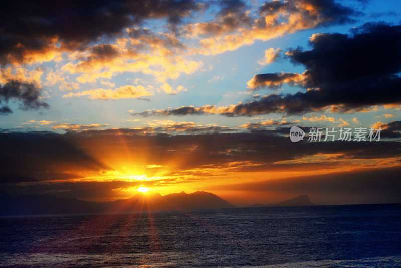 太阳从山上升起，光线反射在海面上