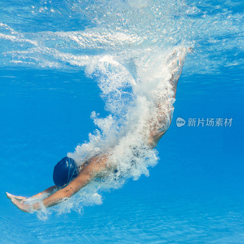 游泳者跳水到一个清澈的蓝色水池