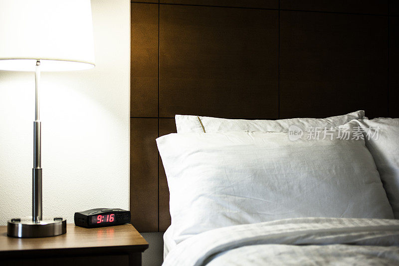 酒店房间的床上有枕头、茶几、台灯和羽绒被。