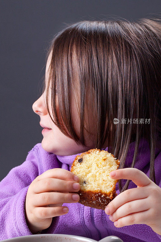小女孩拿着一块蛋糕斜眼看了看