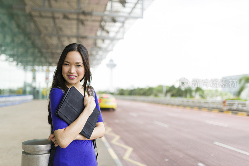 迷人的长发亚洲女人在机场候机厅外等候