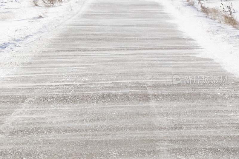 大风把雪吹在柏油路上