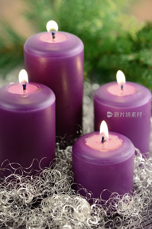 四个紫色的降临节蜡烛，上面燃烧着花环和银色的装饰