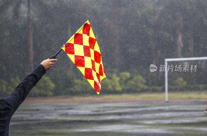 守门员举着角旗，在雨中