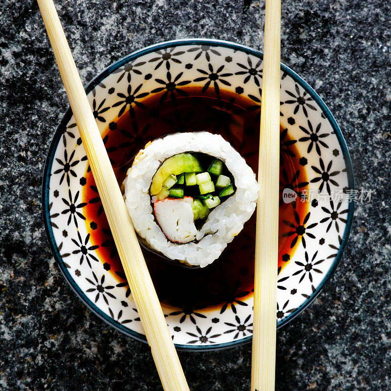 寿司用酱油和筷子卷在盘子里。