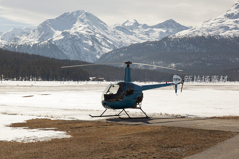 一架蓝色的直升飞机在美丽的山脉和白雪覆盖的风景瑞士阿尔卑斯山