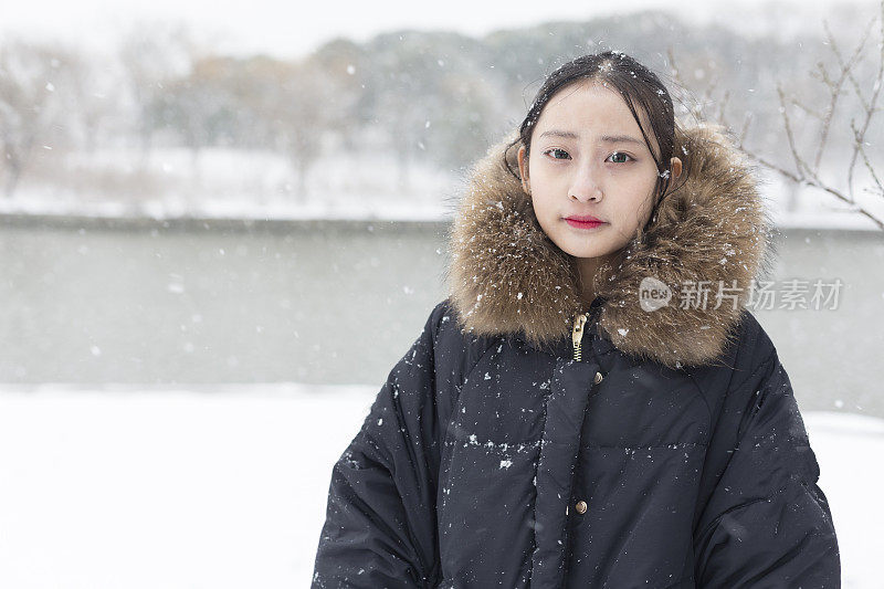 一个美丽的亚洲女人站在雪地里的肖像