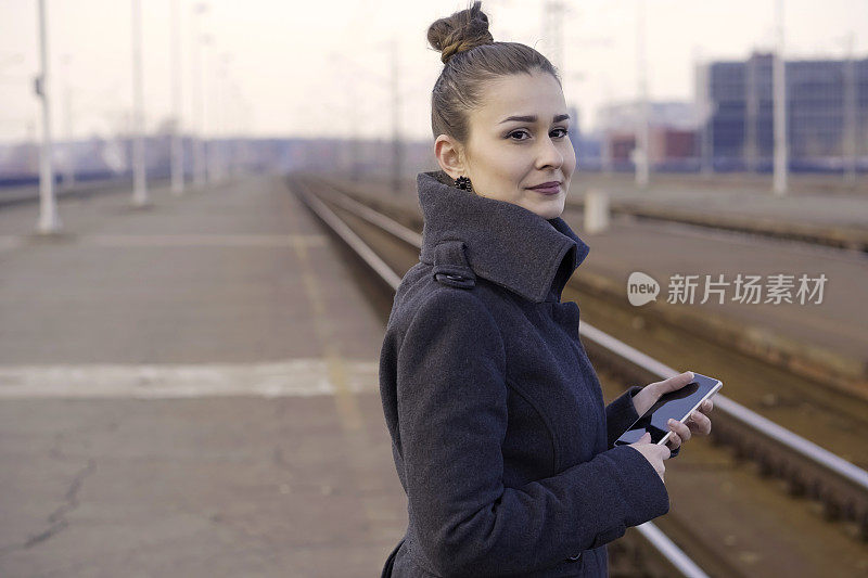 一个年轻女子在火车站用智能手机