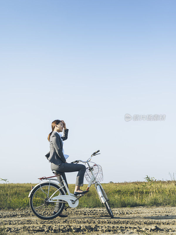 一个年轻的女商人坐在乡下的bicyale上的肖像