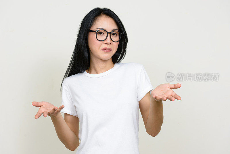 年轻美丽的亚洲女人穿着白色衬衫对抗白色背景