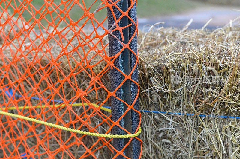 橙色网围栏后面的干草