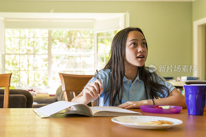 女学生一边做作业一边吃健康食品