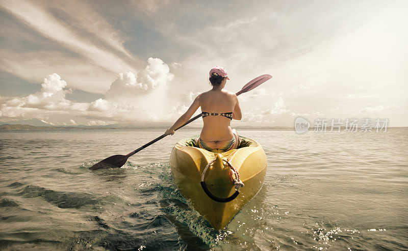女人旅行者探索平静的热带海湾由皮艇。