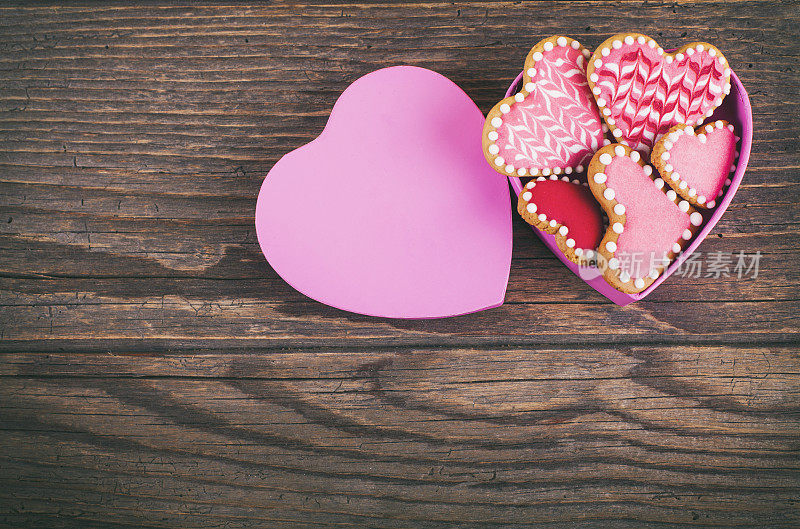 情人节的饼干装在一个心形的盒子里，放在木桌上