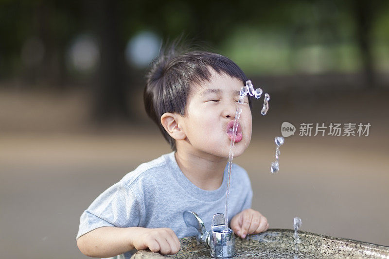 从饮水机里喝水的男孩