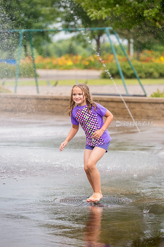 女孩在水喷泉在户外飞溅垫玩