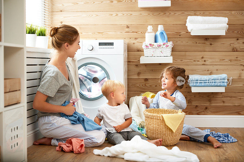 幸福的家庭，母亲，家庭主妇和孩子在洗衣机里洗衣