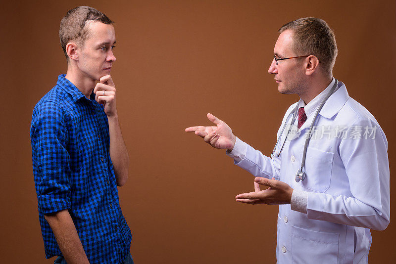 摄影室拍摄的男医生给健康建议的年轻男子病人的彩色背景