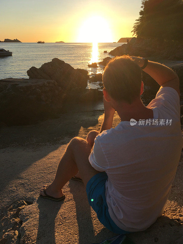 非高峰旅游。克罗地亚杜布罗夫尼克巴宾库克的海岸线上，一名男子正在拍摄日落