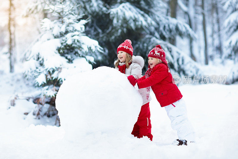 孩子们建造雪人。孩子们在雪。冬天的乐趣。