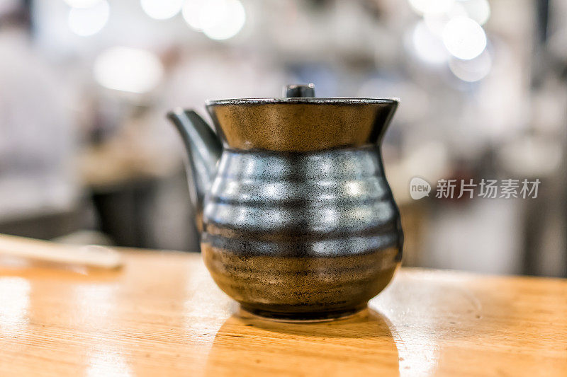 宏观特写的传统黑土日本茶壶茶壶陶瓷在木桌上的咖啡馆餐厅孤立