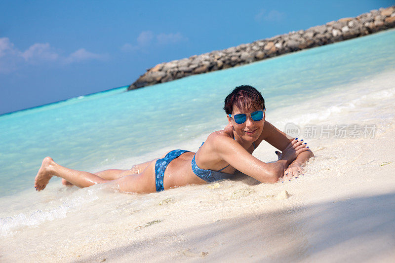 放松的年轻女子享受日光浴在热带海滩
