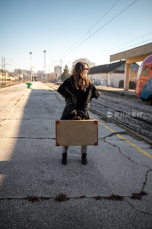 独自行走的年轻女孩提着行李在火车站等待火车