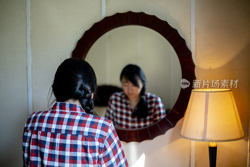 女孩低着头，在镜子前沉思