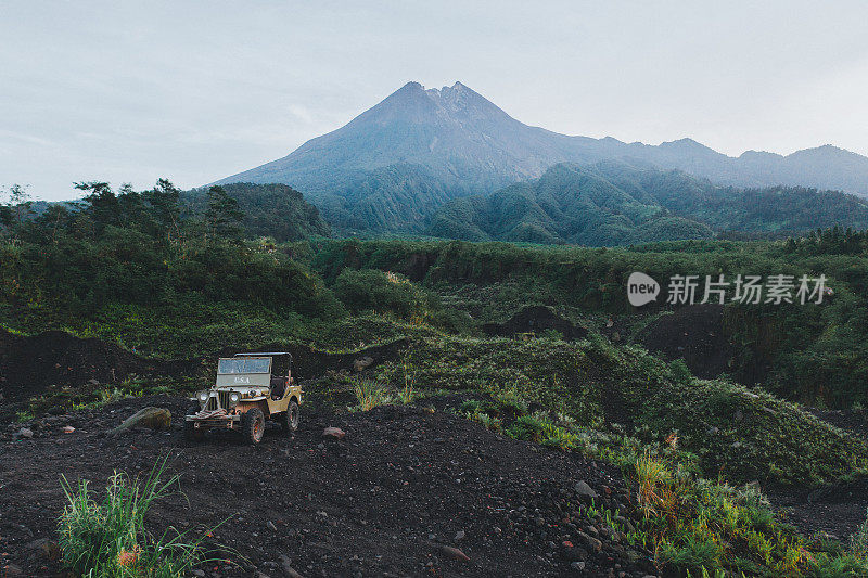 在默拉皮火山的背景上老式SUV的风景鸟瞰图