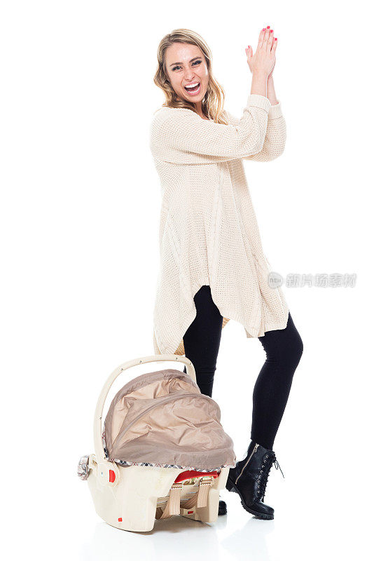 单身母亲穿着一件带有婴儿汽车座椅的毛衣鼓掌