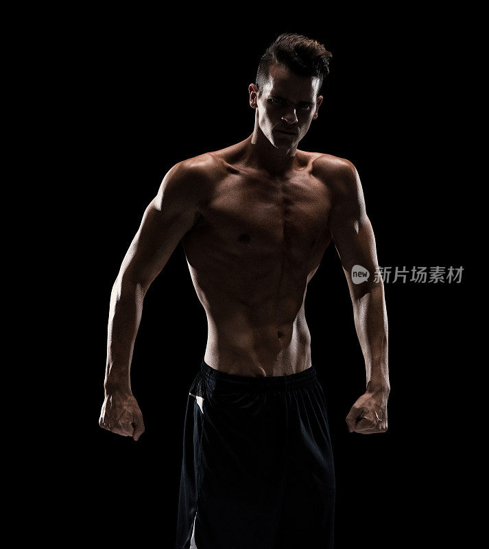 在黑色的背景下，看起来性感的男人和伸缩的肌肉