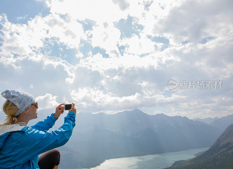 女徒步旅行者从山顶拍摄湖泊和阳光