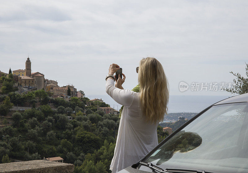 远处村子里的女子在车上用智能手机拍照