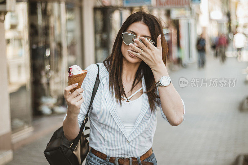 在城市街道上吃着冰淇淋的美女