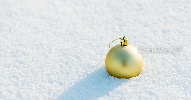 金色的圣诞球在雪地上