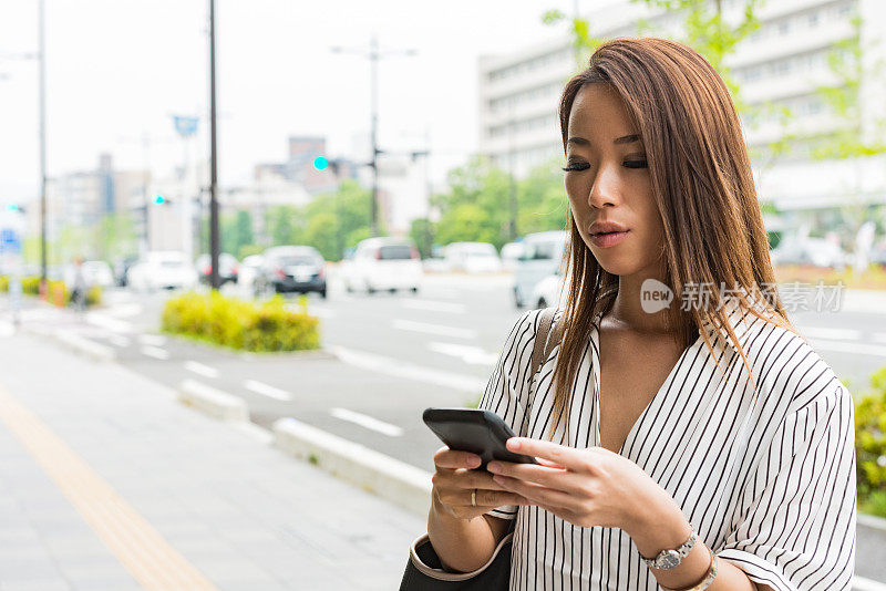 日本京都的千禧女站在户外的街道上玩手机