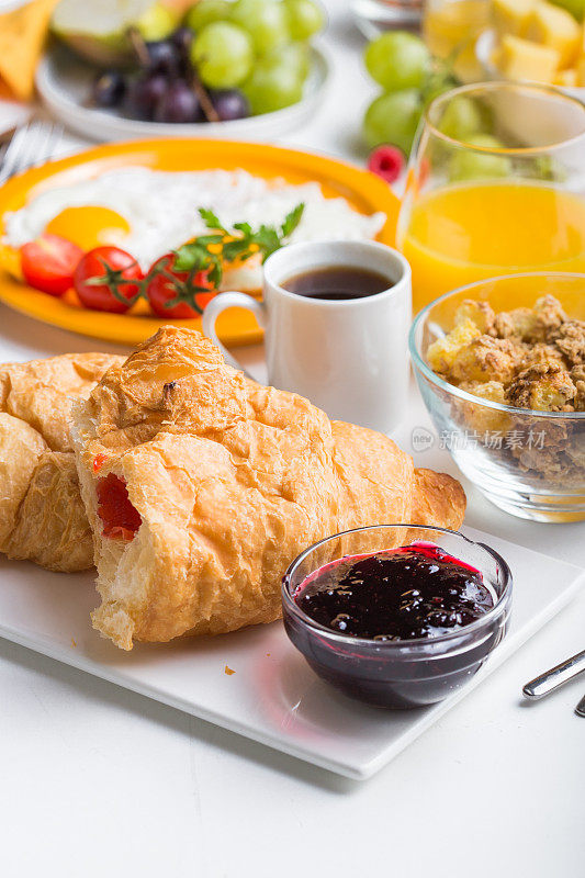 牛角面包和咖啡是早餐的食物和饮料。自制早餐，单面煎蛋，牛角面包，咖啡，水果，蔬菜和橙汁在俯视图与拷贝空间。