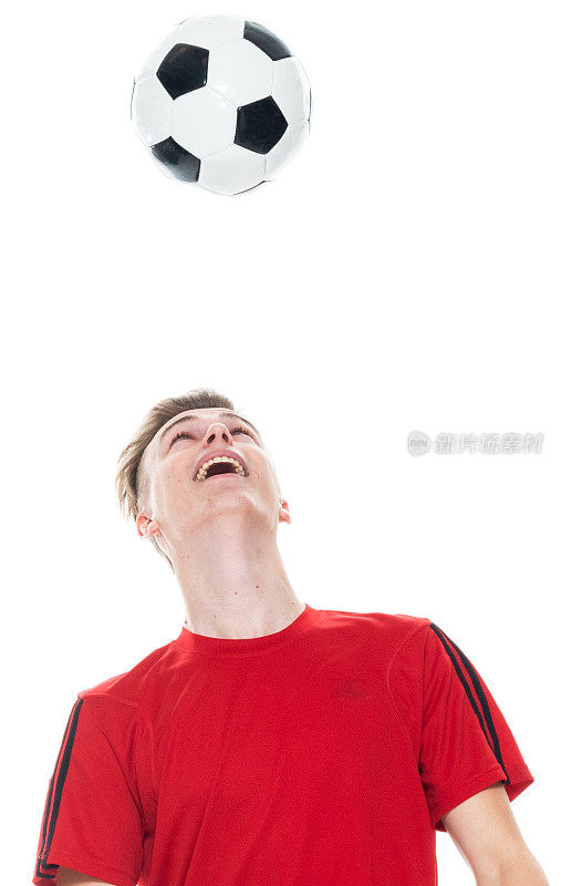 白人男性运动员在白色背景前头球，穿着足球制服，手持足球，进行足球运动和使用运动球