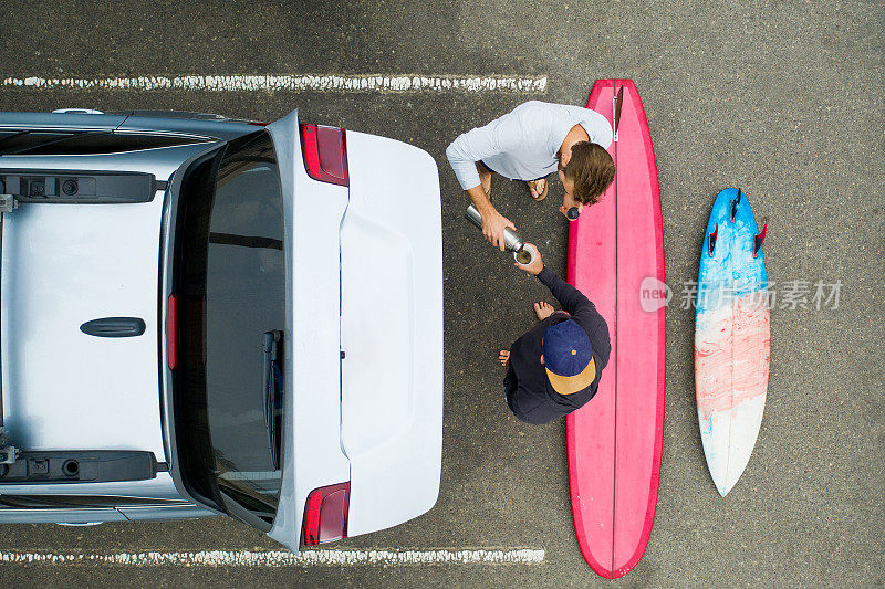 两名冲浪者从屋顶架子上卸下冲浪板-无人机拍摄