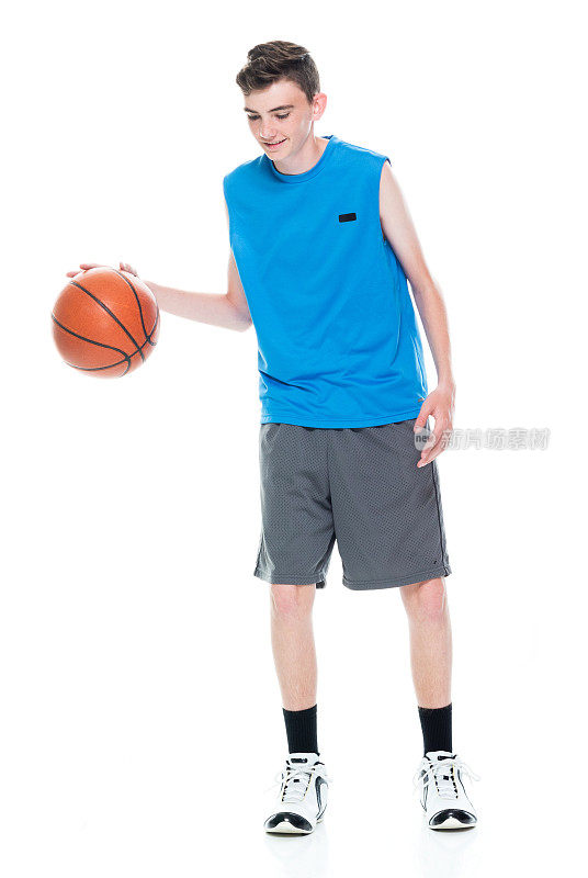 白人少年篮球运动员站在前面的白色背景和拿篮球和使用运动球