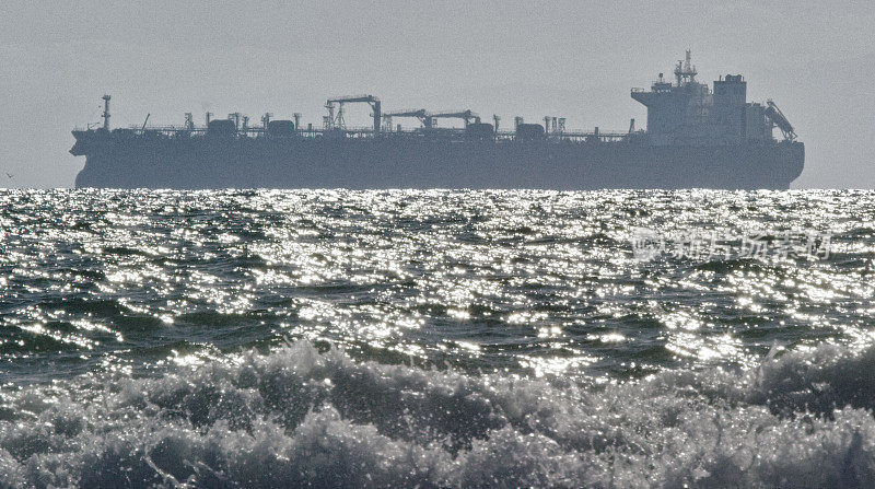 在南加州亨廷顿海滩附近的海浪与地平线上的石油(石油)油轮在远处