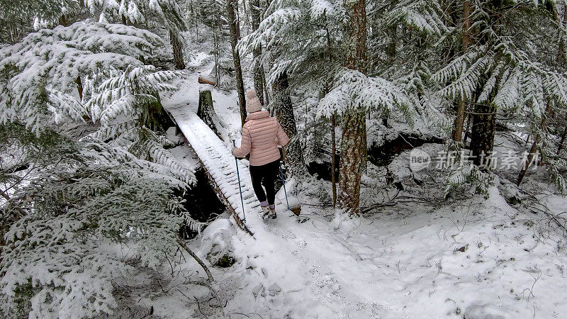 女性徒步旅行者接近积雪覆盖的木板路