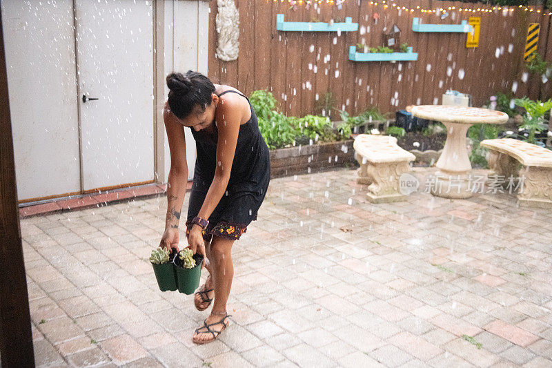 在佛罗里达州，千禧一代的西班牙裔妇女从雨外搬盆栽