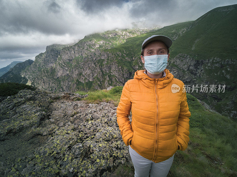 回归自然。新的标准。一个女人独自旅行者的肖像与保护性面具在她的脸上徒步在山上。2019冠状病毒病大流行期间，阳光明媚的户外享受。