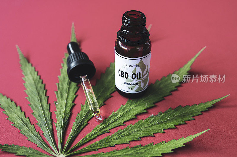 CBD油，医用大麻油在红色的背景。
