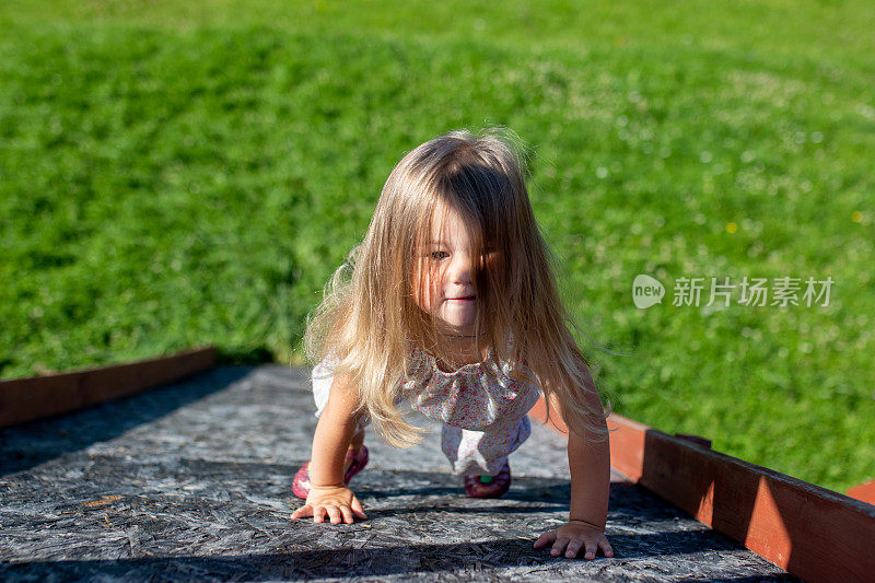 金色长发的小女孩爬上了山。一个狡猾的看。的成就。活跃的娱乐。向上抱负。