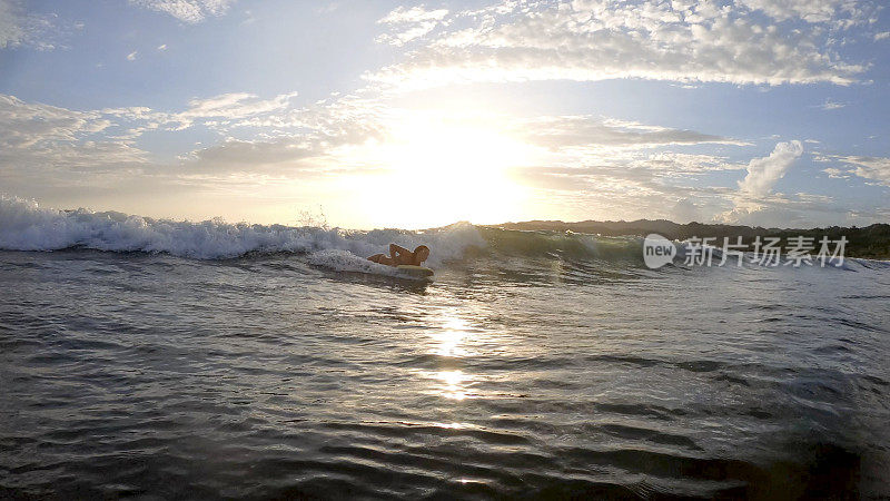 一名年轻女子早上用冲浪板冲浪到岸边