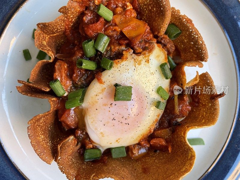 这是地中海健康早餐shakshouka的特写图片，由煎饼和鸡蛋制成，鸡蛋是用西红柿、辣椒、洋葱、橄榄油和大蒜调味的