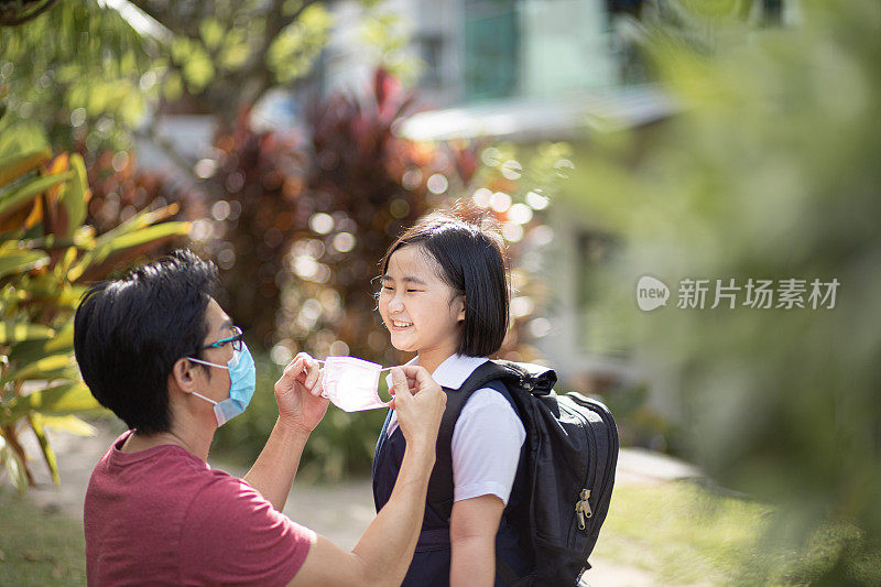 亚洲华人单身父亲帮助女儿戴口罩，以保护后院的流行病